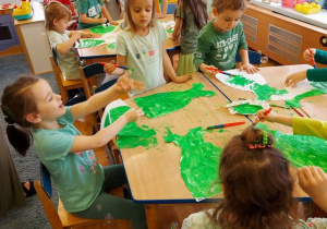 Dzieci malują zieloną farbą sukienki dla pani Wiosny.